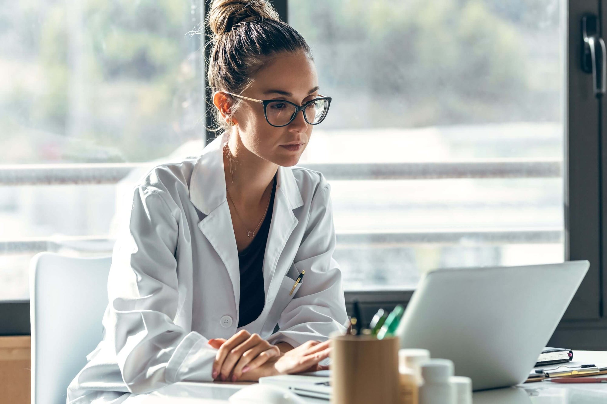 Customer Testimonial - BioV8 customer Dr. Morgan, a psychologist, with glasses, looking at her laptop in her office.