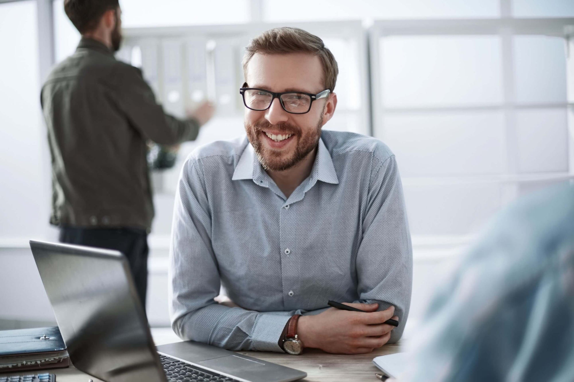 Customer Testimonial - BioV8 customer Steven, a consultant, smiling with glasses in front of a laptop inside an office.