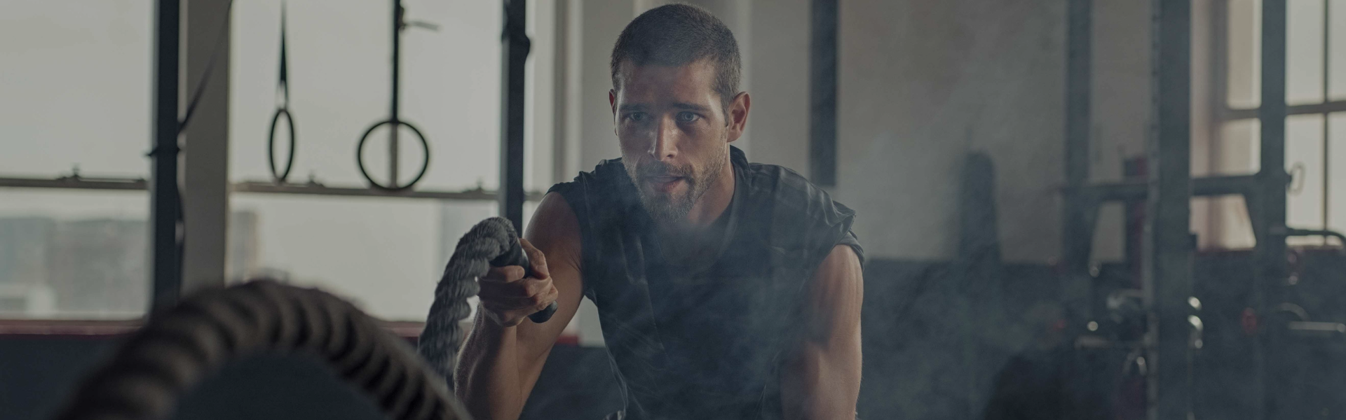 In a gym, a man firmly holds a rope, gearing up for a physical training session.